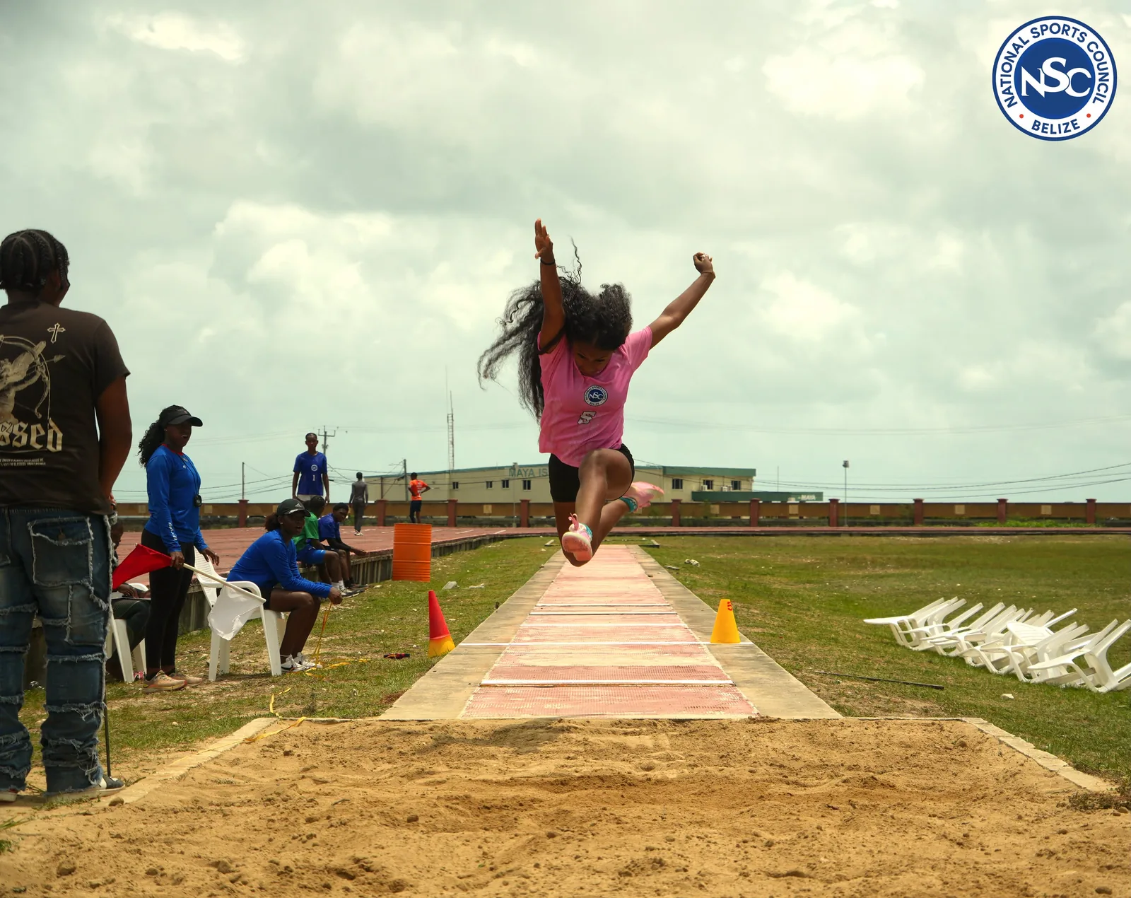 A long jump athlete mid-air over the sand pit at the NSC Super Nationals