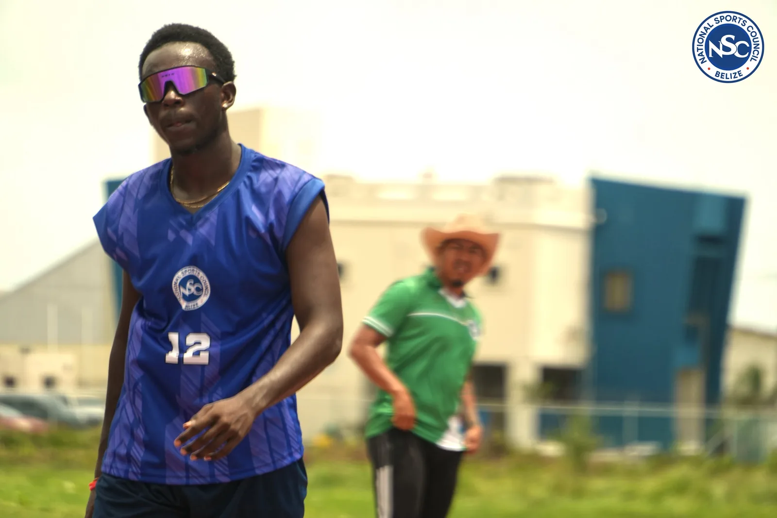 Two athletes in National Sports Council jerseys warming up on the field