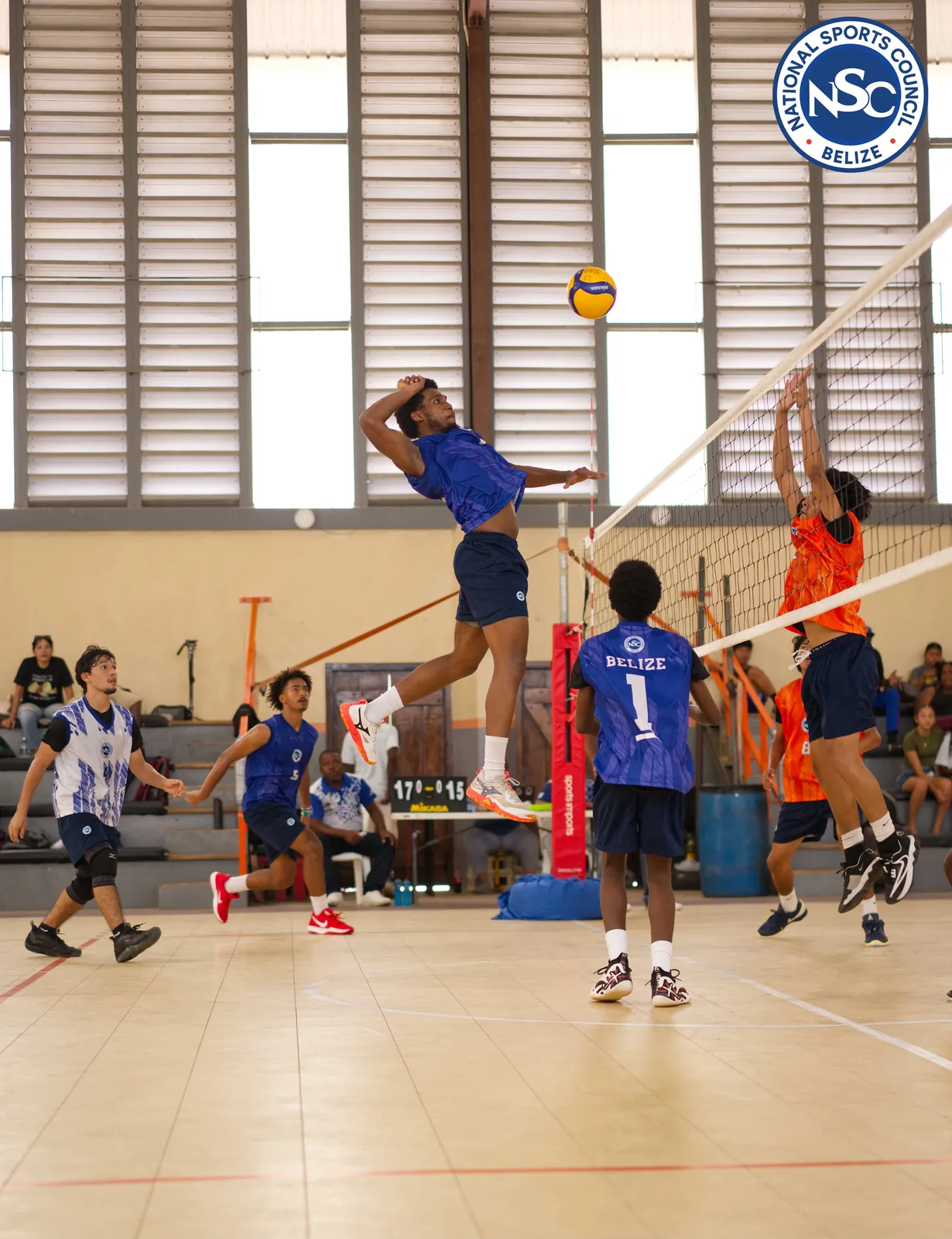 A Belize volleyball player spiking against a block at the net during the NSC Super Nationals